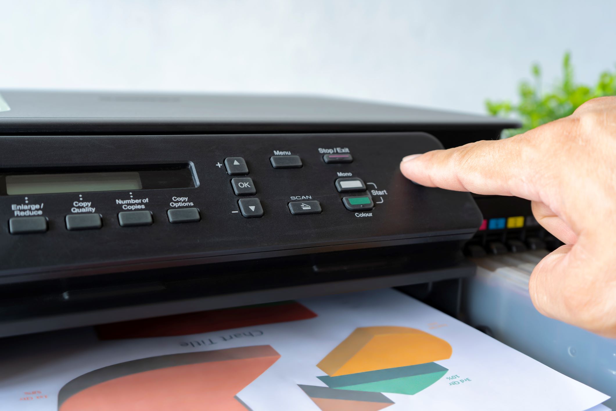 Close-up of a person pressing the start button on a business printer, emphasizing the printer's functionality for producing high-quality business documents.